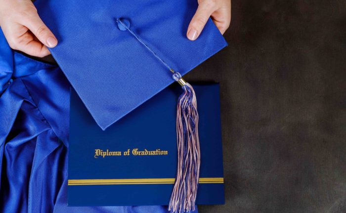 A graduation certificate diploma with graduation hat with empty space over wooden table. selective focus